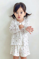 Toddler girl posing in avauma Rosy Cream Flower Cardigan and matching shorts set, smiling indoors.